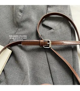 Détail de la bandoulière réglable en cuir marron foncé avec boucle en métal argenté