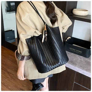 Close-up of black woven leather tote bag with stylish wooden bead tassel detail