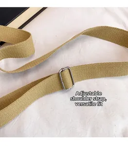 Dettaglio della tracolla regolabile in tela beige con fibbia in metallo argento