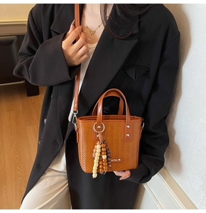 Détail du tissage sur un mini sac cabas marron avec pompon et bandoulière réglable