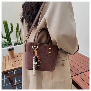 Détail du sac seau en daim vintage avec surpiqûres et pendentif à pampilles en bois