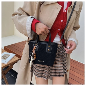 Détail du sac seau en daim noir avec coutures matelassées et rivets dorés