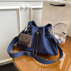 Dettaglio borsa a secchiello in tela blu navy con pochette in pelle marrone e tracolla