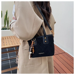 Détail du sac seau noir en daim matelassé avec breloque en perles de bois et boucle dorée