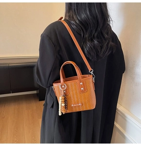 Détail du mini sac seau tressé marron caramel avec des perles en bois décoratives