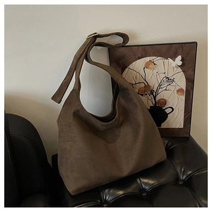Detail of dark brown suede hobo bag featuring premium gold buckle and wide shoulder strap