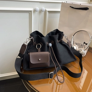 Dettaglio borsa a secchiello in tela con coulisse, finiture in pelle e mini custodia
