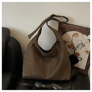 Detailed view of the soft brown suede fabric texture and adjustable shoulder strap buckle