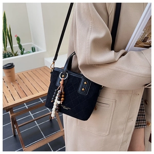 Détail du sac seau en daim noir matelassé avec lettrage doré et pampille de perles