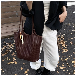 Detail of dark brown woven tote bag with bead charms in an autumn outdoor setting
