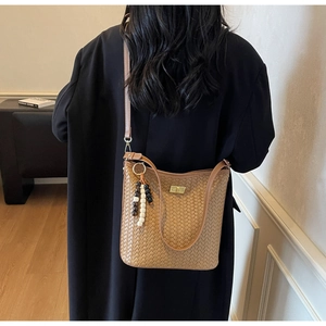 Detail der braunen geflochtenen Eimertasche mit Goldschließe und Perlenverzierung