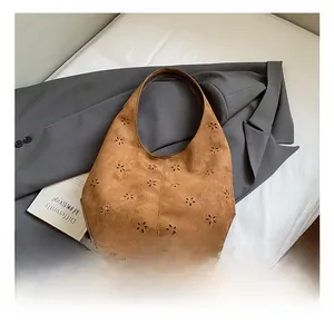 Detail of laser-cut floral patterns on camel suede hobo bag for a bohemian touch