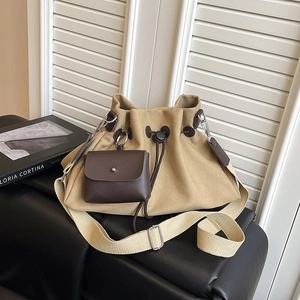 Dettaglio della borsa a secchiello in tela kaki con tasca in pelle e tracolla larga