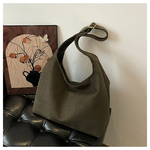 Macro shot of dark green suede hobo bag detailing the golden metal buckle on wide strap