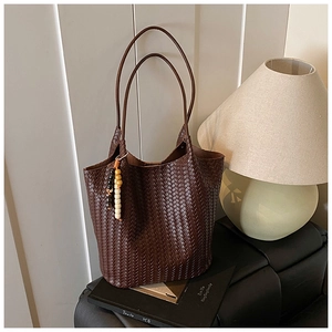 Detailed view of dark brown woven leather tote with beaded charm on a photography book