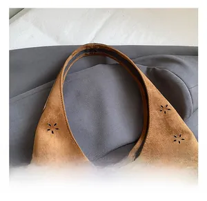 Close-up of the intricate laser-cut floral patterns on brown faux suede tote bag