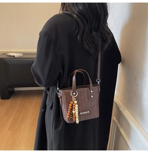 Détail du mini sac seau tressé marron foncé avec bandoulière cuir et perles en bois