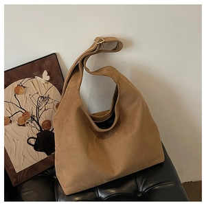 Detail of a large brown suede hobo bag featuring an adjustable strap and metal buckle