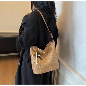 Nahaufnahme der gewebten Schultertasche mit Perlenanhänger und goldenem Drehverschluss