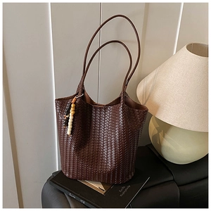 Close-up of dark brown woven tote bag featuring decorative colored bead pendant