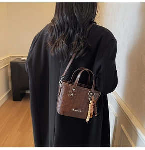 Gros plan détaillé du sac cabas marron foncé à texture tissée avec breloque perlée