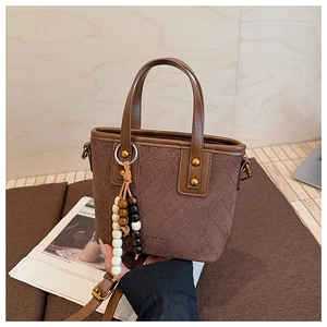 Détails du sac seau en daim marron vintage avec surpiqûres losanges et bijou de sac
