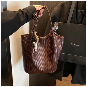 Close-up of woven leather tote bag with unique wood bead tassel and rich texture details