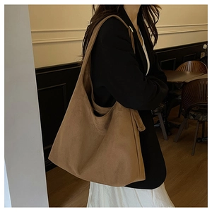 Brown suede tote bag worn by a model in a cozy cafe, showing large capacity and soft texture