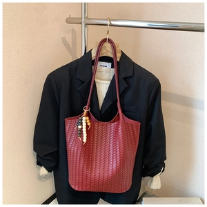 Detailed view of red woven leather tote bag with colorful beaded charm and long strap