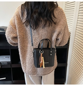 Détail du motif chevron sur sac à bandoulière noir avec perles en bois décoratives