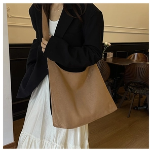 Detail of caramel suede tote bag with wide strap and soft texture on female model