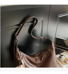 Close-up of vintage brown hobo tote with adjustable strap and decorative plush ball charm