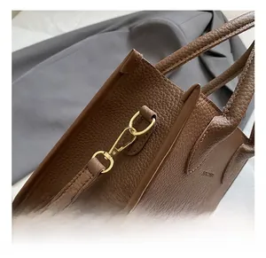 Close-up of premium brown lychee grain leather with golden metal carabiner hook details