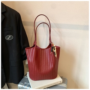 Detailed close-up of dark red woven leather tote bag with stylish beaded tassel charm