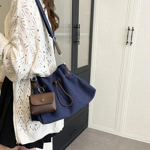 Dettaglio borsa a secchiello in tela blu navy con coulisse in pelle marrone e mini pochette