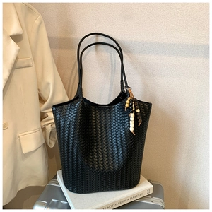Detail of black woven leather tote bag with wooden bead tassel and long shoulder straps