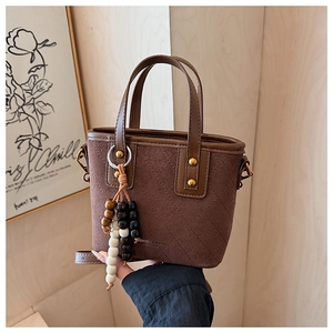 Détail d'un sac seau en daim vintage avec matelassage en losange et pompon de perles