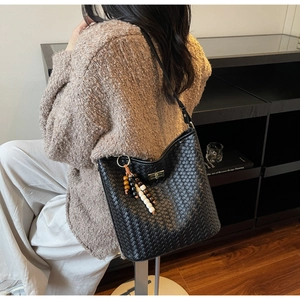 Detail einer gewebten schwarzen Beuteltasche mit Metallschnalle und Perlenquaste