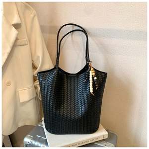 Detail of black woven leather tote bag with decorative wooden bead fringe charm
