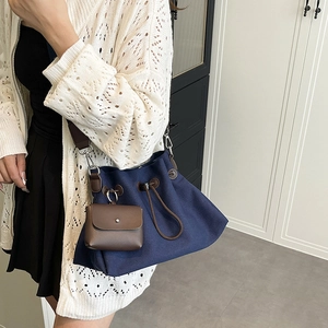 Dettaglio borsa a secchiello in tela blu navy con coulisse in pelle e piccola bustina rimovibile