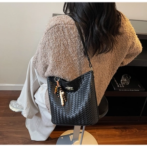 Detail der schwarzen geflochtenen Beuteltasche mit Perlenquaste, von Model getragen