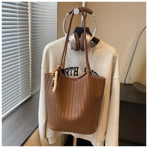 Detailed woven texture of coffee brown tote bag with beaded tassel charm on a display