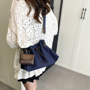 Dettaglio borsa a secchiello in tela blu navy con finiture in pelle marrone e mini pochette