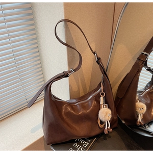 Détail d'un sac hobo marron foncé avec texture vintage et charmant pendentif en peluche