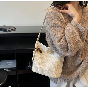 Detail der weißen geflochtenen Hobo-Tasche mit goldenem Drehverschluss und bunten Perlen