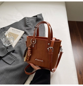 Détail du sac marron à texture tressée avec pompon en perles de bois et plaque métal