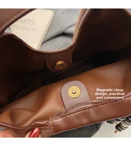 Dettaglio della chiusura magnetica in ottone vintage su una borsa a secchiello marrone