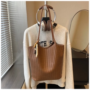 Detailed woven texture of brown leather tote bag with wooden bead charm detail