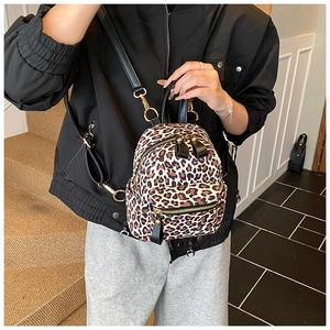Detailed view of mini leopard print backpack featuring gold zippers and black straps