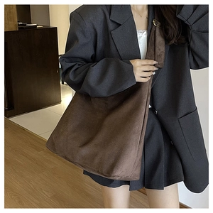 Macro detail of high-capacity dark brown suede tote bag with matte texture on shoulder